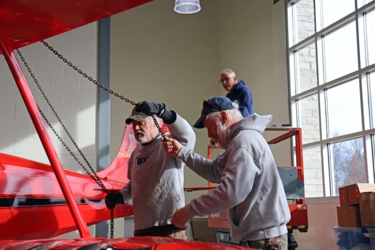 Volunteers and staff working together to hang the Rose Parrakeet that now "flies" in the Wagner Welcome Atrium.